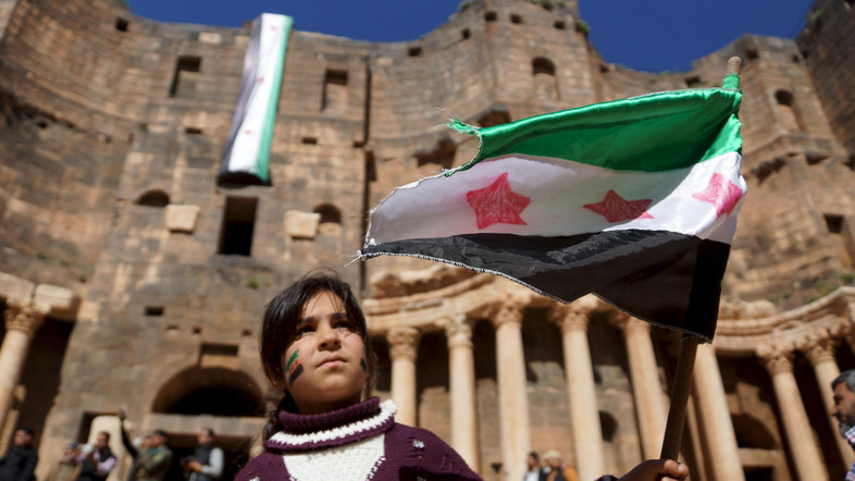 A girl waves an opposition flag during an anti-government protest inside a 2nd century Roman amphitheater in the historic Syrian southern town of Bosra al-Sham, in Deraa